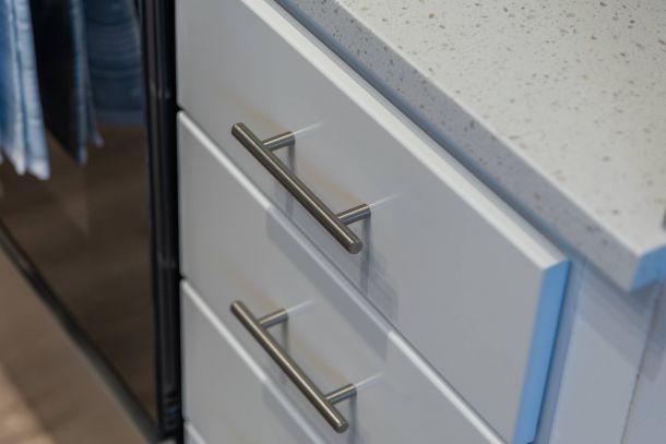 Acclaim at the Hill senior apartment homes with Close-up of white kitchen drawers with silver handles next to a speckled white countertop.