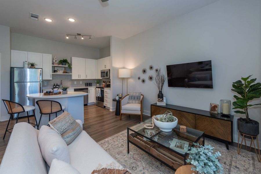 Acclaim at the Hill senior apartment homes with Modern open-concept living room and kitchen with neutral decor, indoor plants, and wall-mounted TV.