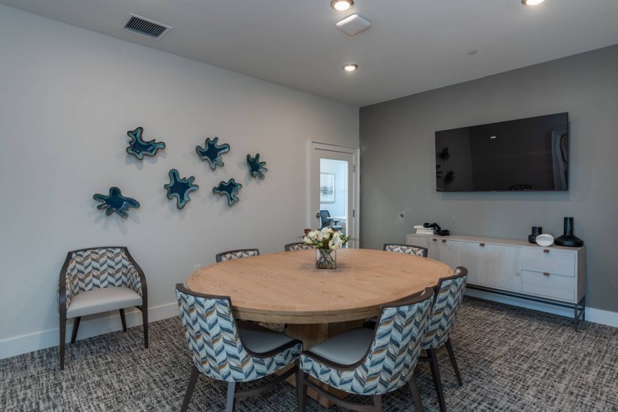 Acclaim at the Hill senior apartment homes with Modern meeting room with a round table, six chairs, wall art, a TV, and a sideboard with decor.
