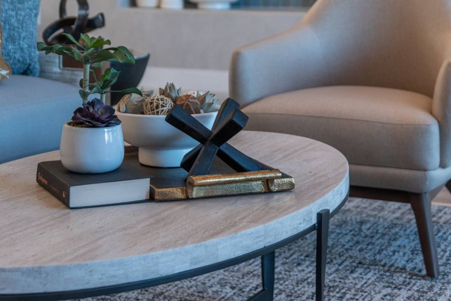 Acclaim at the Hill senior apartment homes with Modern living room with a beige armchair, coffee table, potted plants, and a TV mounted on the wall.