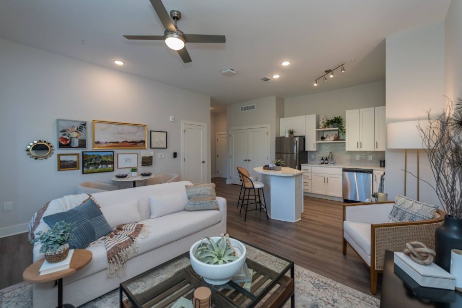 Acclaim at the Hill senior apartment homes with Modern open-concept living room and kitchen with neutral decor, indoor plants, and cozy seating arrangements.